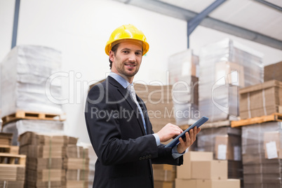 Warehouse manager wearing hard hat using tablet