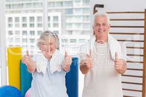 Senior couple gesturing thumbs up in gym