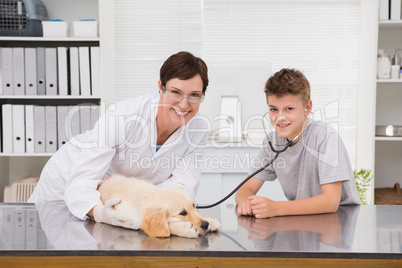 Smiling vet examining a dog with its owner