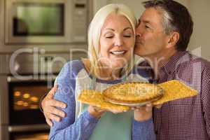 Mature blonde holding fresh pie with husband kissing her