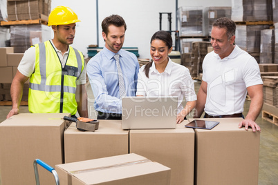 Warehouse managers and worker looking at laptop