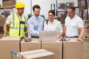 Warehouse managers and worker looking at laptop