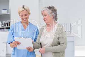 Nurse and senior patient discussing over clipboard
