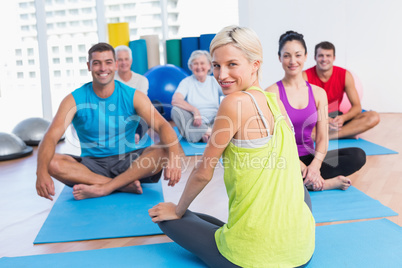 Instructor with class practicing yoga in fitness studio