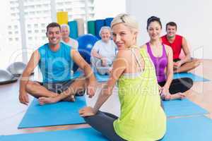 Instructor with class practicing yoga in fitness studio
