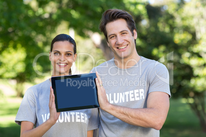 Happy volunteer couple holding tablet pc