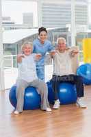Senior couple on exercis ball with trainer