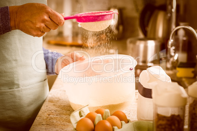 Woman sieving flour into bowl