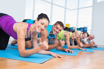 People gesturing thumbs up while lying on exercise mats