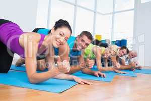 People gesturing thumbs up while lying on exercise mats