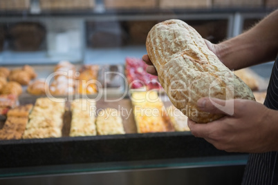 Worker in apron holding fresh loaf