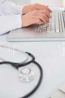 Doctor using laptop near stethoscope