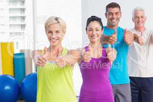 Fit people gesturing thumbs up at gym