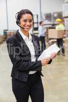 Warehouse manager wearing headset holding clipboard