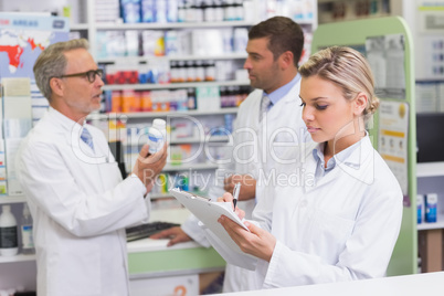 Focused pharmacist writing on clipboard Focused pharmacist writing on clipboard