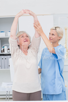 Nurse assisting female patient in raising arms