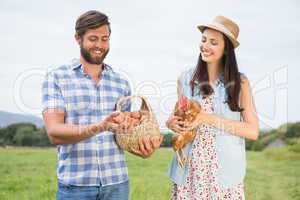 Happy farmers holding chicken and eggs