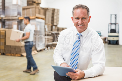 Boss using digital tablet in warehouse