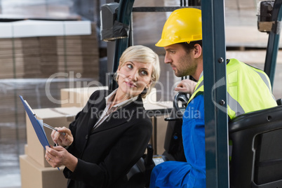 Warehouse manager talking with forklift driver