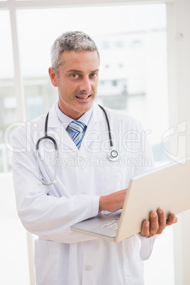 Doctor using laptop smiling to camera