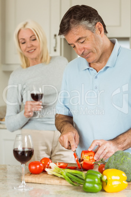 Happy mature couple having red wine while making dinner