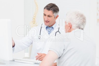 Doctor explaining reports to senior patient on computer