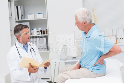 Doctor discussing reports with patient suffering from backache