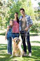 Happy family walking their dog in the park