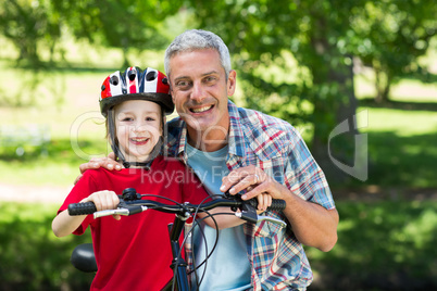 Happy little boy on his bike with his father