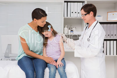 Doctor doing injection at a little girl with her mother