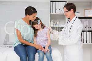 Doctor doing injection at a little girl with her mother