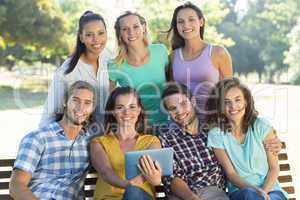 Smiling friends in the park using tablet pc