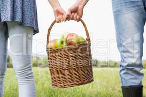 Couple holding basket full of apples