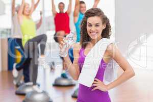 Happy woman holding water bottle in gym