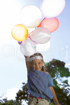 Happy little girl holding balloons