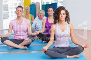 Women practicing lotus position in gym