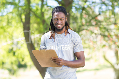 Happy volunteer in the park holding clipboard