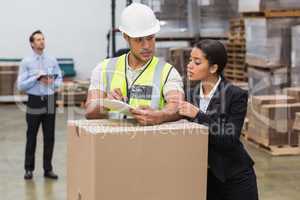 Warehouse manager and worker looking at clipboard