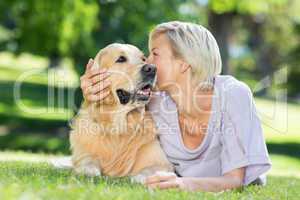 Pretty blonde kissing her dog in the park