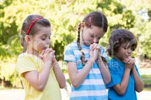 Children saying their prayers in park