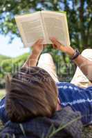 Handsome hipster reading book in park