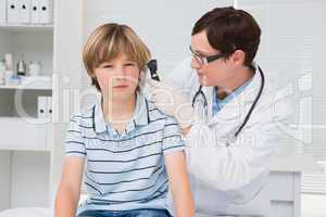 Doctor examining a little boy with otoscope