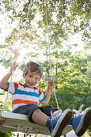 Happy little boy on a swing in the park