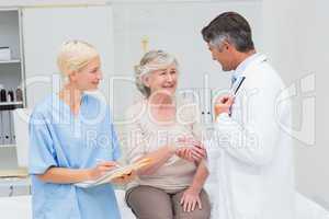 Doctor and patient shaking hands while nurse writing reports