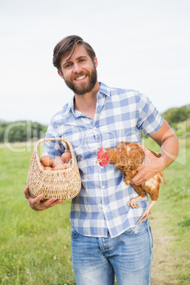 Happy farmer holding chicken and eggs