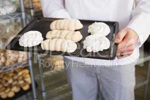 Mid section of baker holding meringue tray