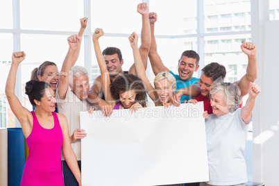 Excited people holding blank billboard at gym