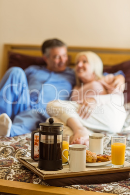 Happy mature couple having breakfast in bed