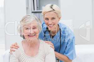 Nurse with hands on senior patients shoulders in clinic