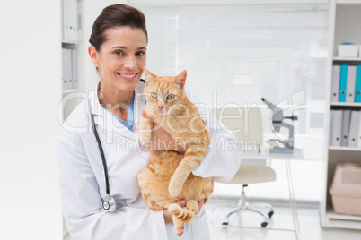 Smiling veterinarian with a cute cat in her arms